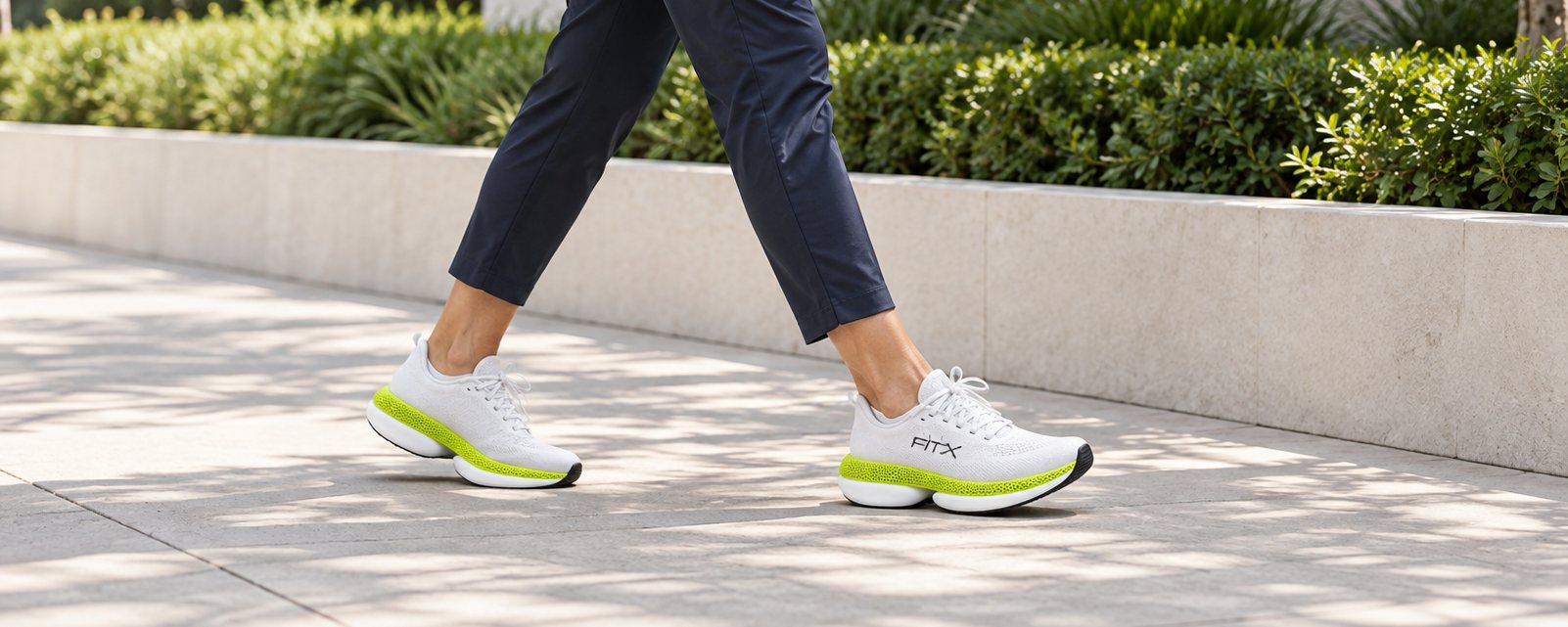 Person walking along a garden path in white FitX 01 running shoes.